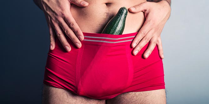 Torso of a man wearing red briefs with a cucumber poking out the top