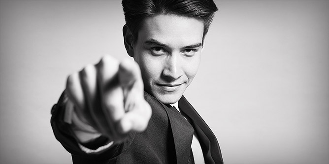 Young man in a suit staring at the camera and pointing 