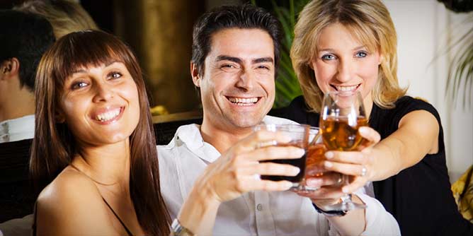 Monogamish swinger couple flirting with a single female over drinks 
