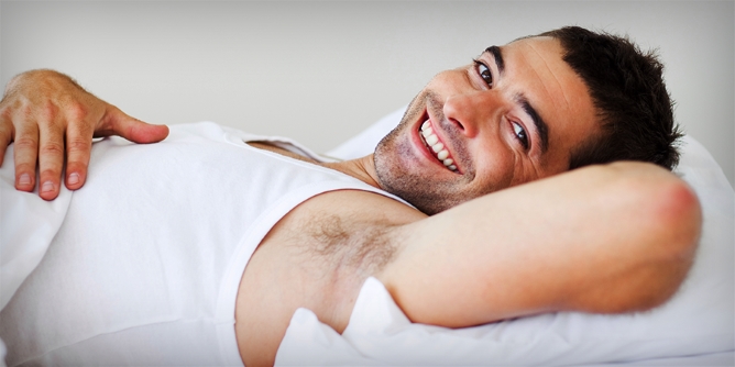 Handsome unshaven man in bed smiling at the camera