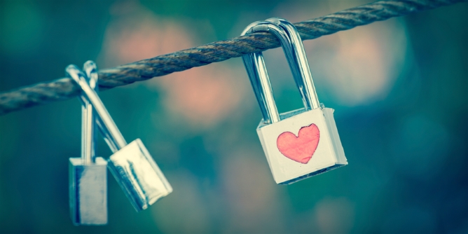 Silver lock engraved with a red heart hanging on a wire