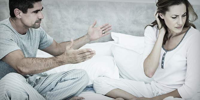 Couple wearing pyjamas in bed having an argument