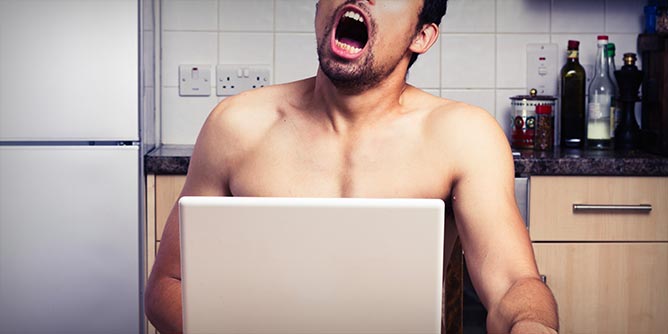 Man sitting at the kitchen table watching porn on his laptop