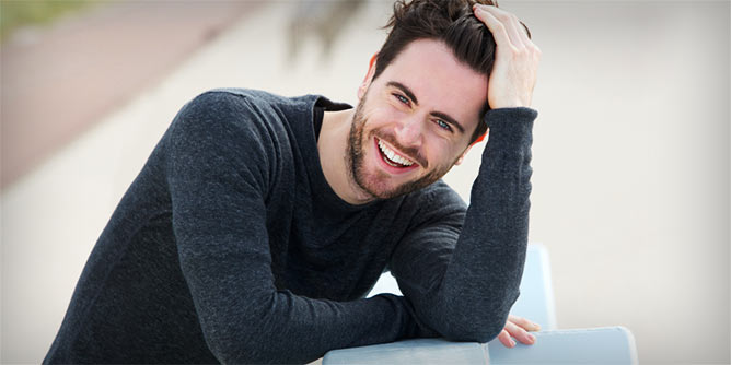 Young man leaning on a fence and laughing