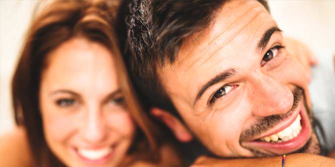 Close up of man and woman smiling at the camera after hearing a joke