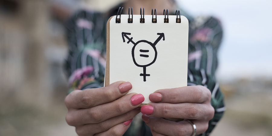 Trans person holding up a notepad with the transgender symbol