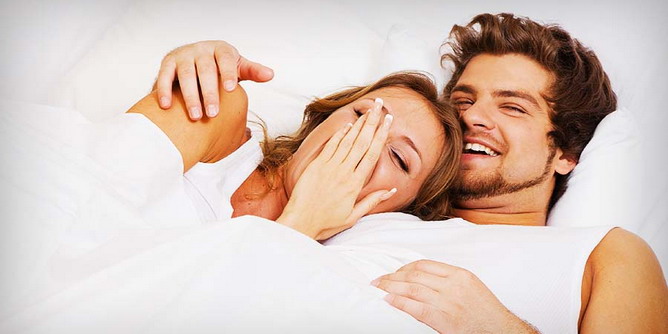 Couple sharing a laugh as they cuddle in bed
