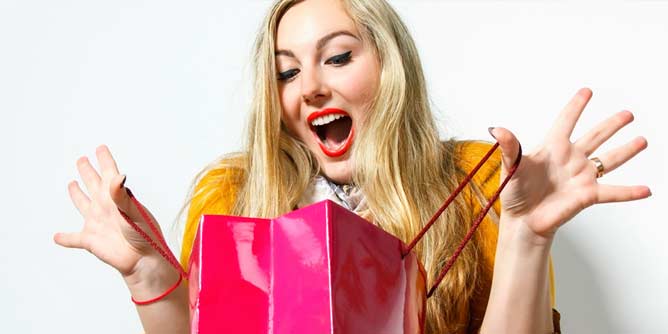 Excited woman opening a gift bag containing a sex toy