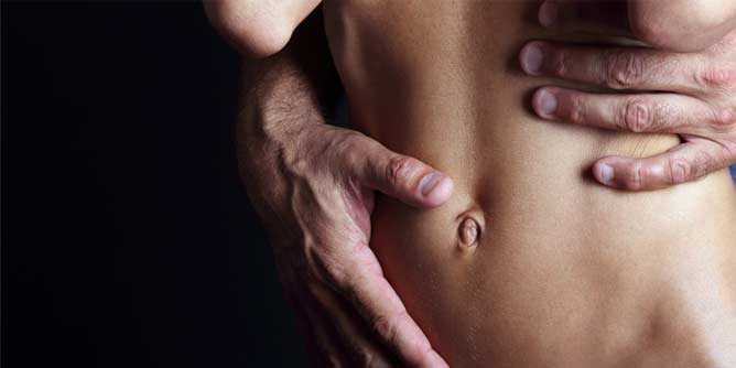 Close up of a man's hands caressing a woman's bare stomach