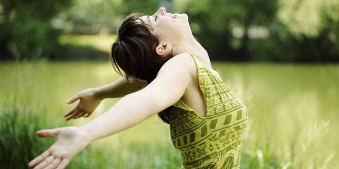 Woman looking up at the sky with her arms outstretched letting nothing hold her back