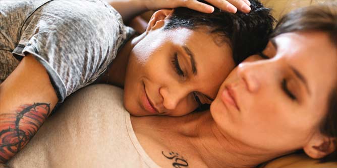 Two bisexual women sharing a cuddle in bed 