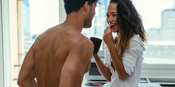 Young couple who are friends with benefits sharing a laugh and a coffee in the morning