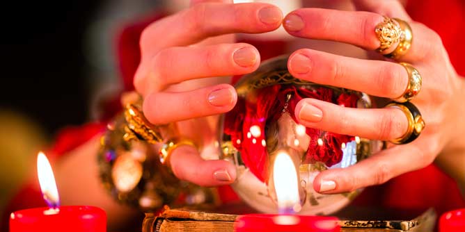 Gypsy holding her hands around a crystal ball to predict what will happen in the year ahead