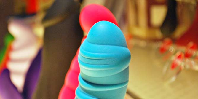 Row of colourful silicone sex toys on display in an adult store