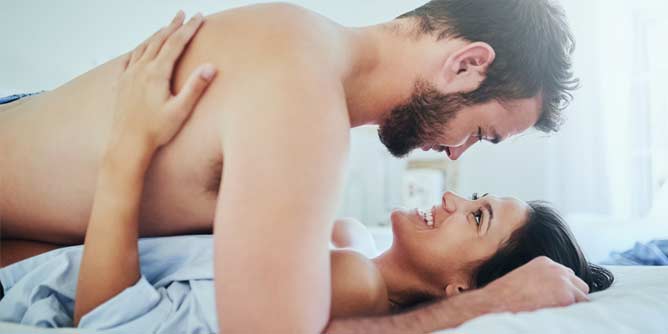 Man and woman sharing an intimate moment in bed and smiling at each other