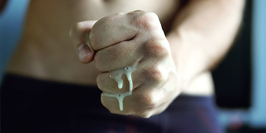 Man's fist clenched and a creamy liquid squeezing out between his fingers