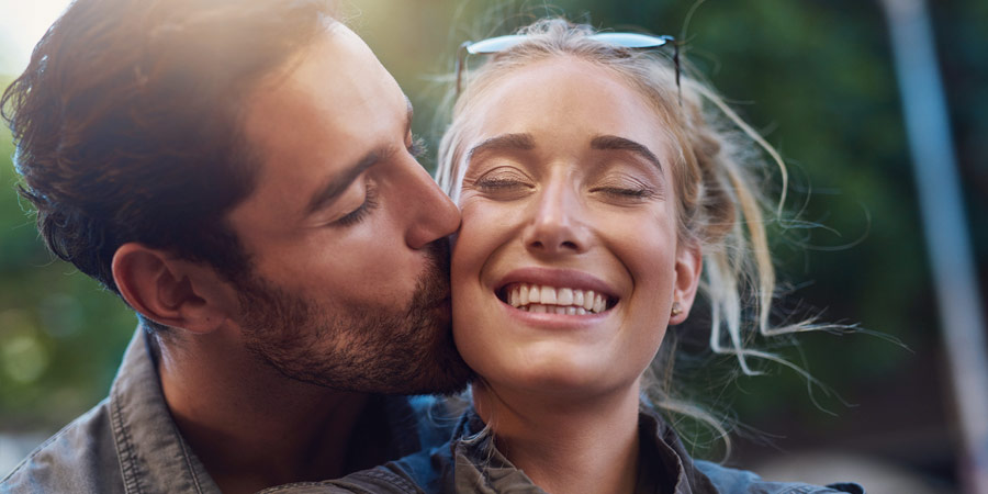 Man kissing his partner on the cheek and making her smile
