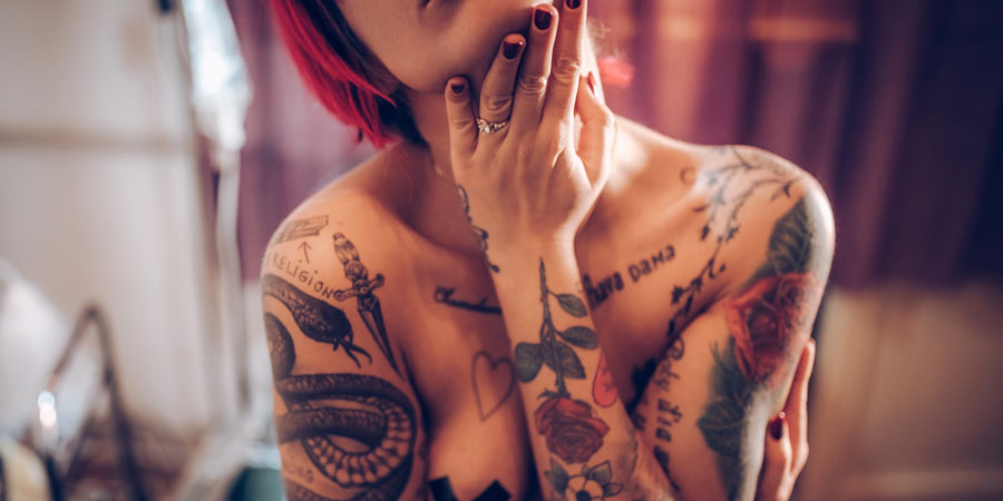 Attractive brunette woman who is into body modification with multiple tattoos across her arms and chest