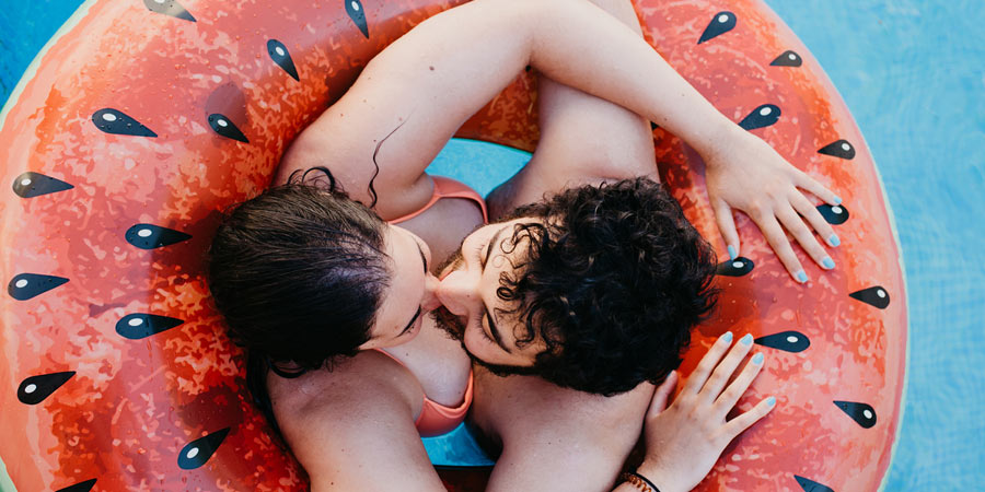 Attractive young couple kissing in a swimming pool over the holidays