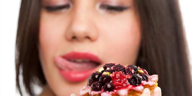 Close up of a woman licking her lips before she eats a cake
