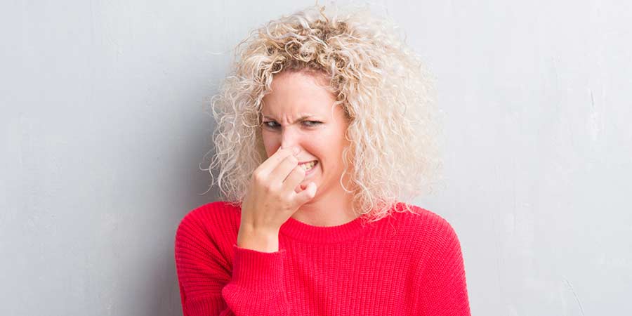 Woman scrunching up her face and holding her nose because she just farted