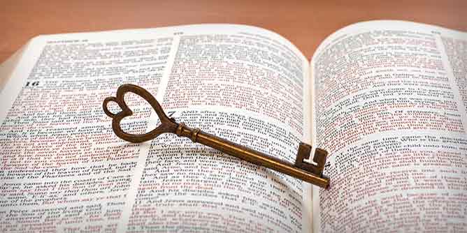 Antique key sitting on open Christian bible