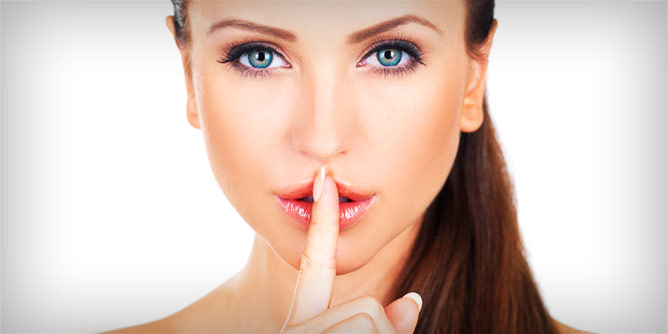 Woman with her finger to her lips to signify keeping a secret