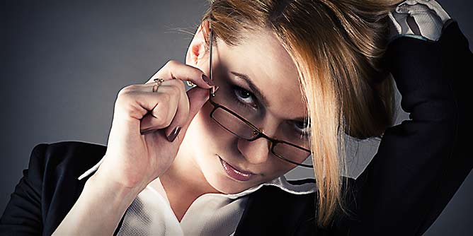 Sexy professional woman in a suit and glasses looking enticingly at the camera